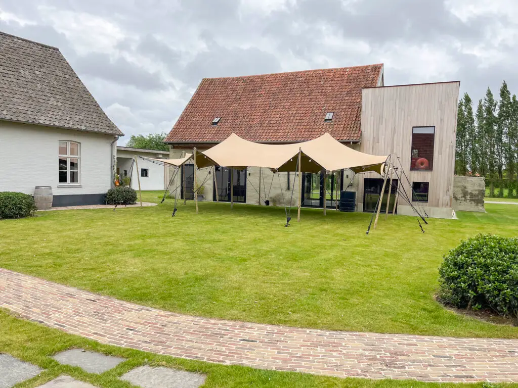 Beige stretchtent in de tuin van een woning, opgezet voor een tuinfeest