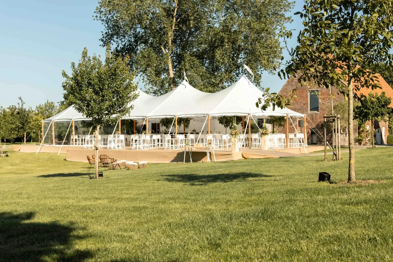 Sailcloth tent met witte stoelen in een tuin