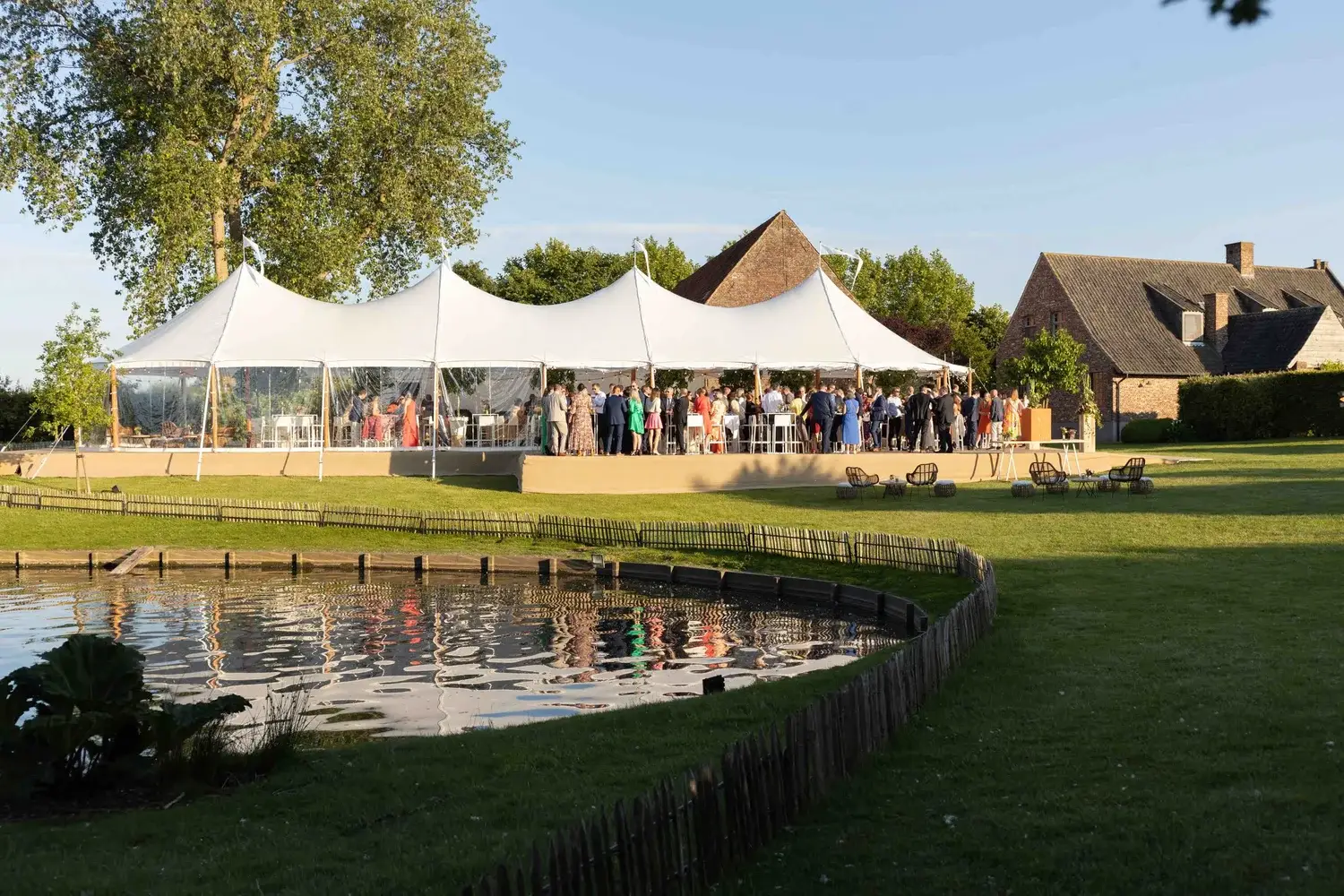 Sailcloth tent met gasten aan de rand van een vijver