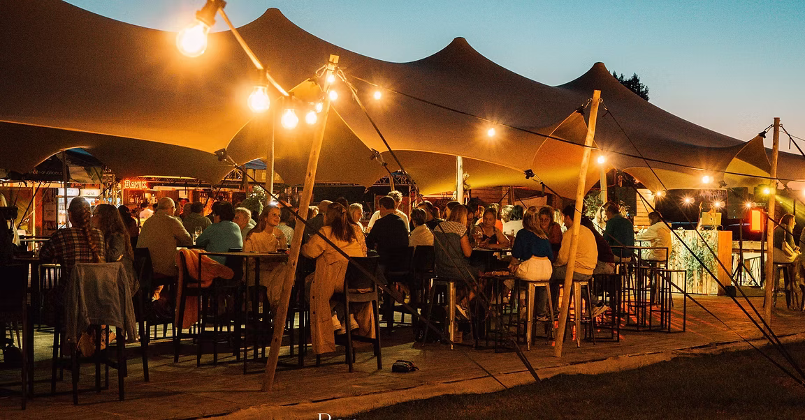 Stretchtent met lichtsnoeren 's avonds, vol feestende gasten